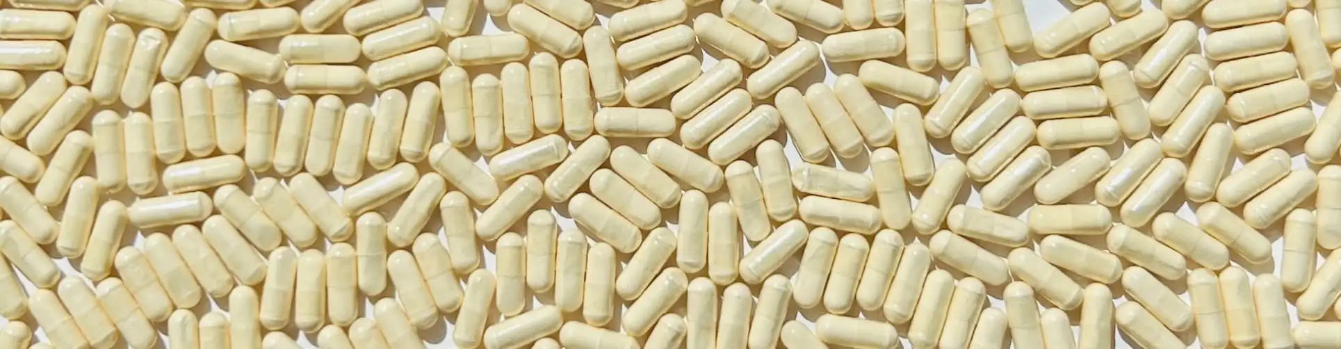 Beige cylindrical capsules scattered across a surface.